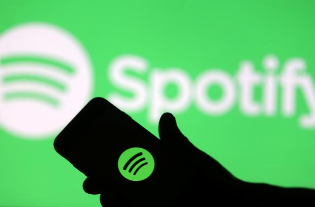 A smartphone is seen in front of a screen projection of Spotify logo, in this picture illustration taken April 1, 2018. REUTERS/Dado Ruvic/Illustration