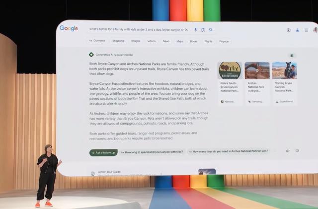 Still from Google's 2023 I/O presentation on SGE. A presenter stands on the stage with a huge slide behind her showing AI-generated results in Google search.